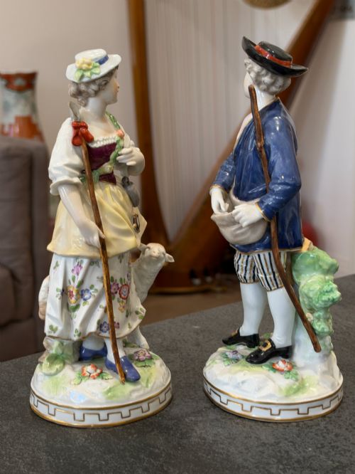 fig 4. A pair of antique hand-painted German porcelain figures depicting a shepherdess with a lamb and a shepherd holding a basket, set on circular gilded bases.