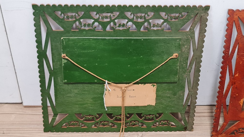 A pair of framed three-dimensional wooden folk art pictures featuring rural village scenes set within fretted reddish-brown frames. View V