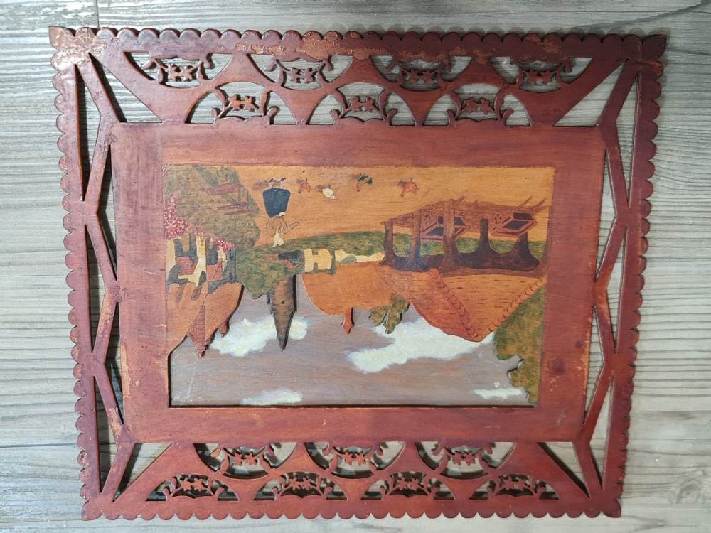 A pair of framed three-dimensional wooden folk art pictures featuring rural village scenes set within fretted reddish-brown frames. View X