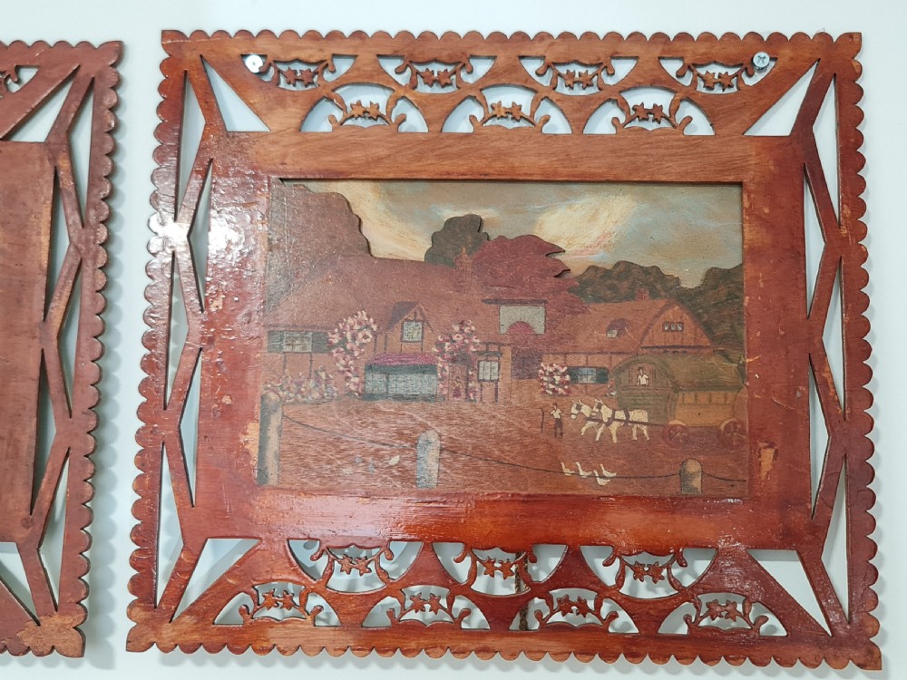 A pair of framed three-dimensional wooden folk art pictures featuring rural village scenes set within fretted reddish-brown frames. View XII