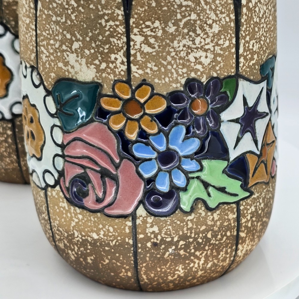 A pair of cylindrical Austrian ceramic vases featuring a textured beige ground, black rim, vertical cutouts, and colourful enamelled floral bands. View III