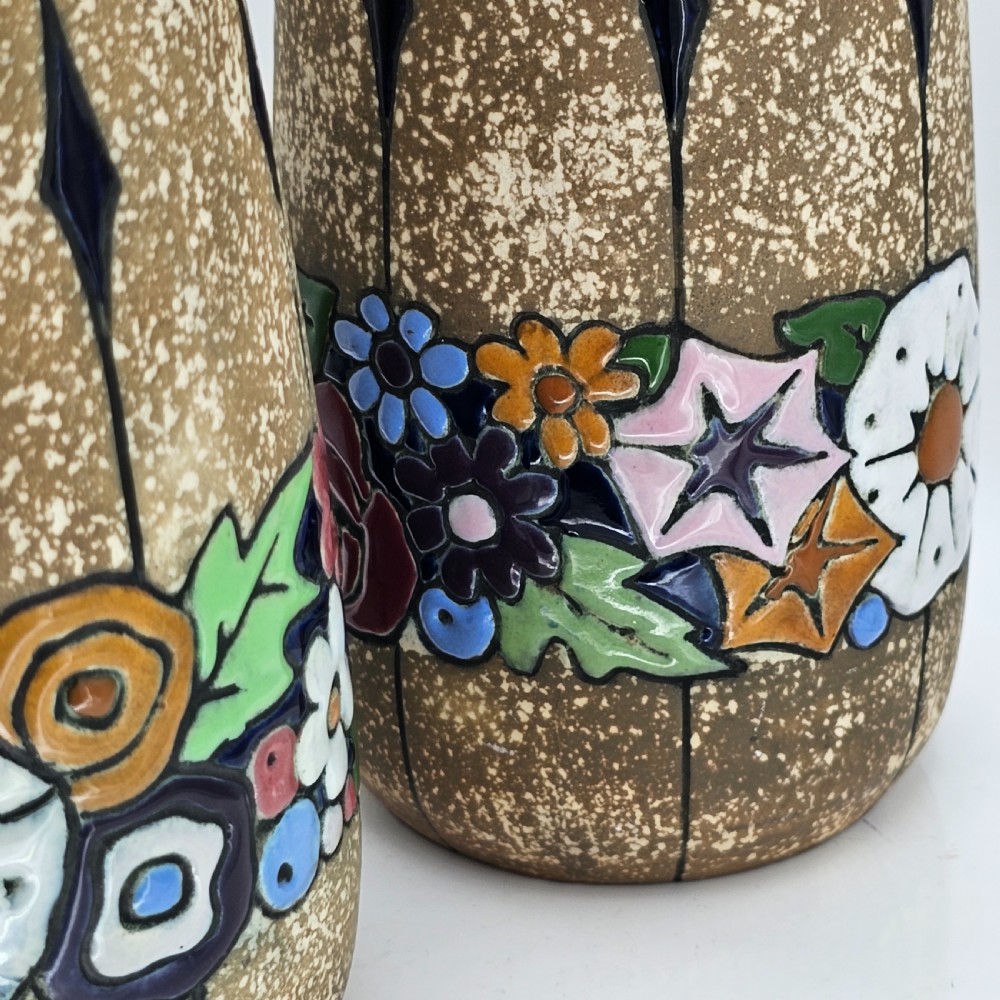 A pair of cylindrical Austrian ceramic vases featuring a textured beige ground, black rim, vertical cutouts, and colourful enamelled floral bands. View VII