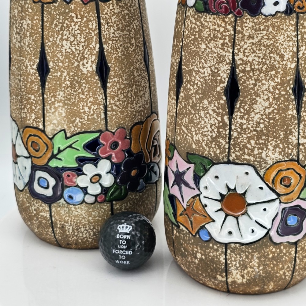 A pair of cylindrical Austrian ceramic vases featuring a textured beige ground, black rim, vertical cutouts, and colourful enamelled floral bands. View VIII