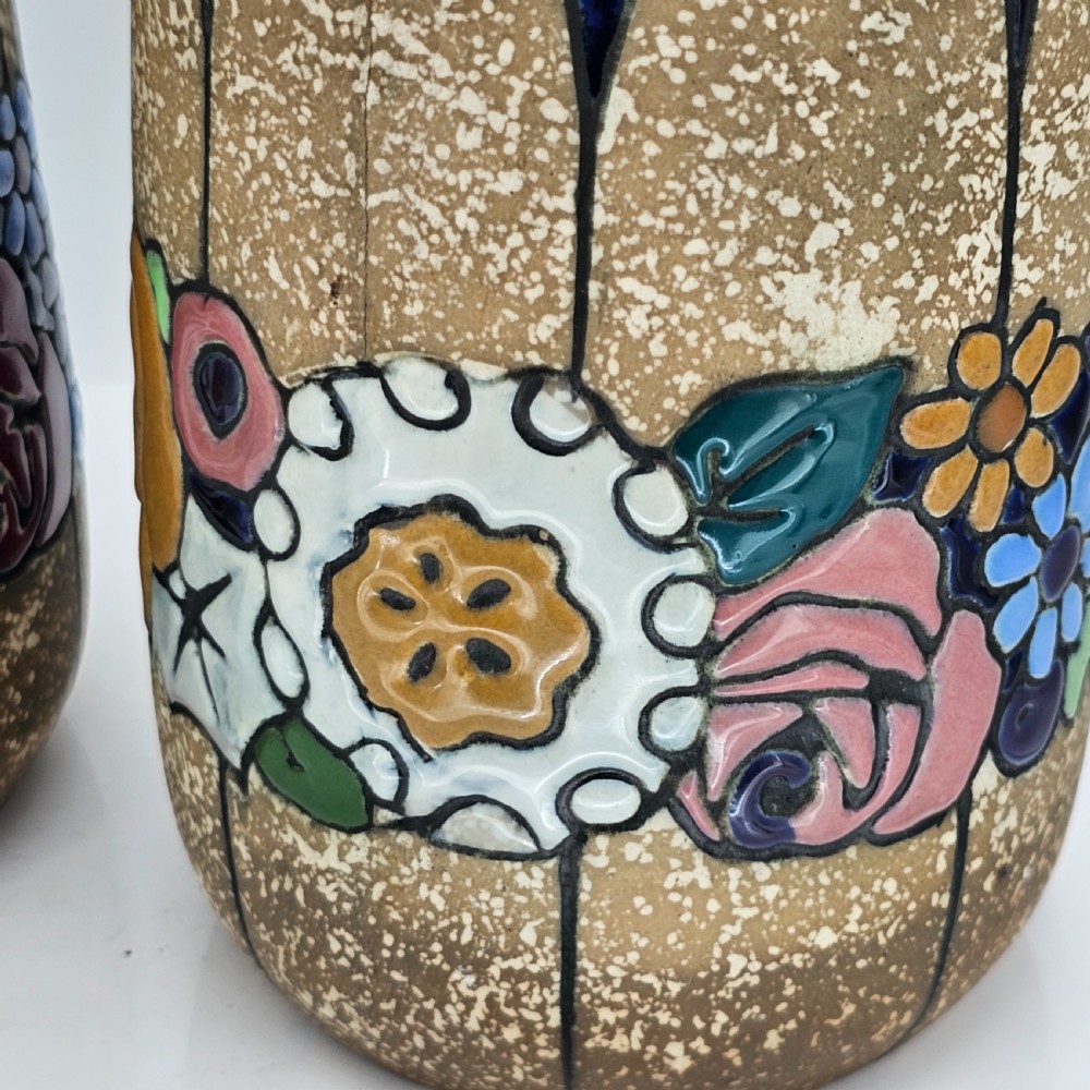 A pair of cylindrical Austrian ceramic vases featuring a textured beige ground, black rim, vertical cutouts, and colourful enamelled floral bands. View XI