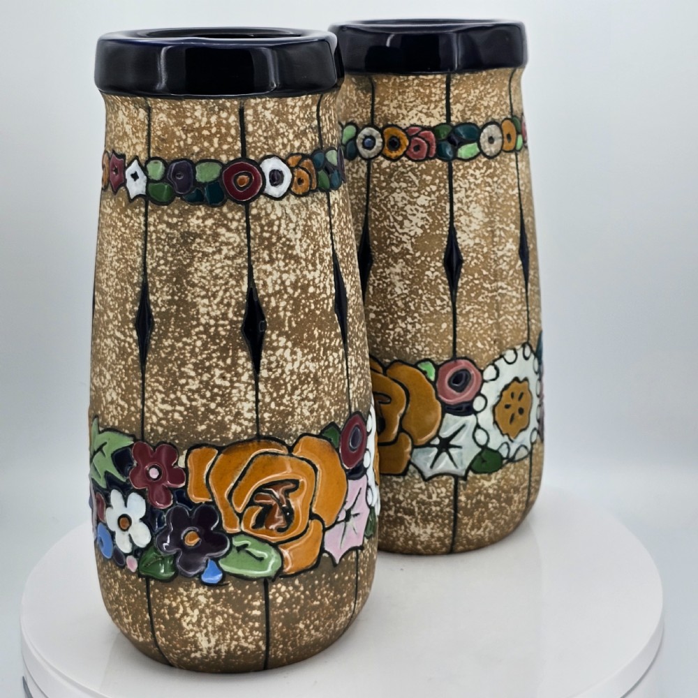 A pair of cylindrical Austrian ceramic vases featuring a textured beige ground, black rim, vertical cutouts, and colourful enamelled floral bands. View XVI