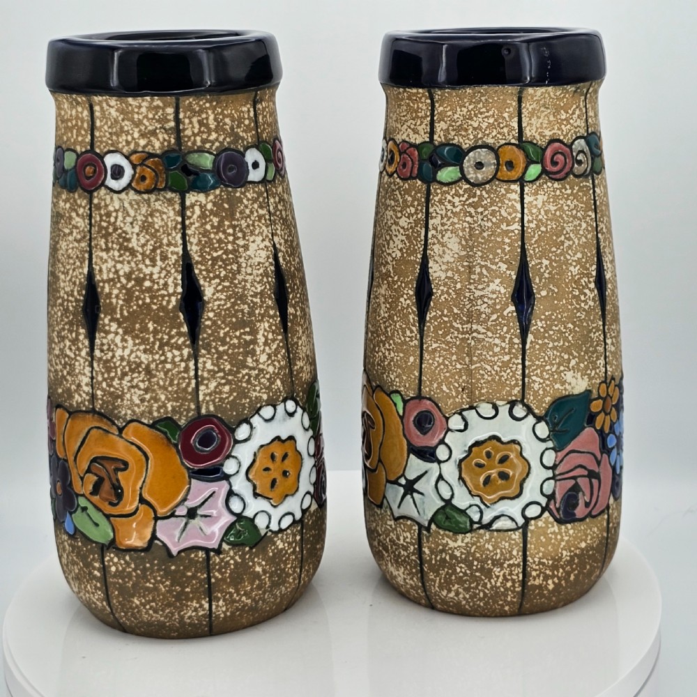 A pair of cylindrical Austrian ceramic vases featuring a textured beige ground, black rim, vertical cutouts, and colourful enamelled floral bands. View XVII