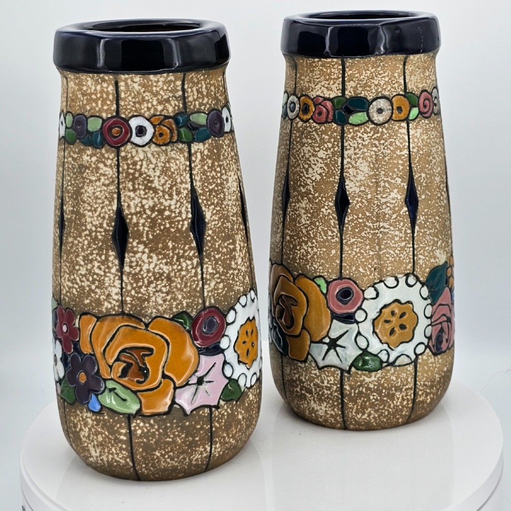 A pair of cylindrical Austrian ceramic vases featuring a textured beige ground, black rim, vertical cutouts, and colourful enamelled floral bands. View XIX