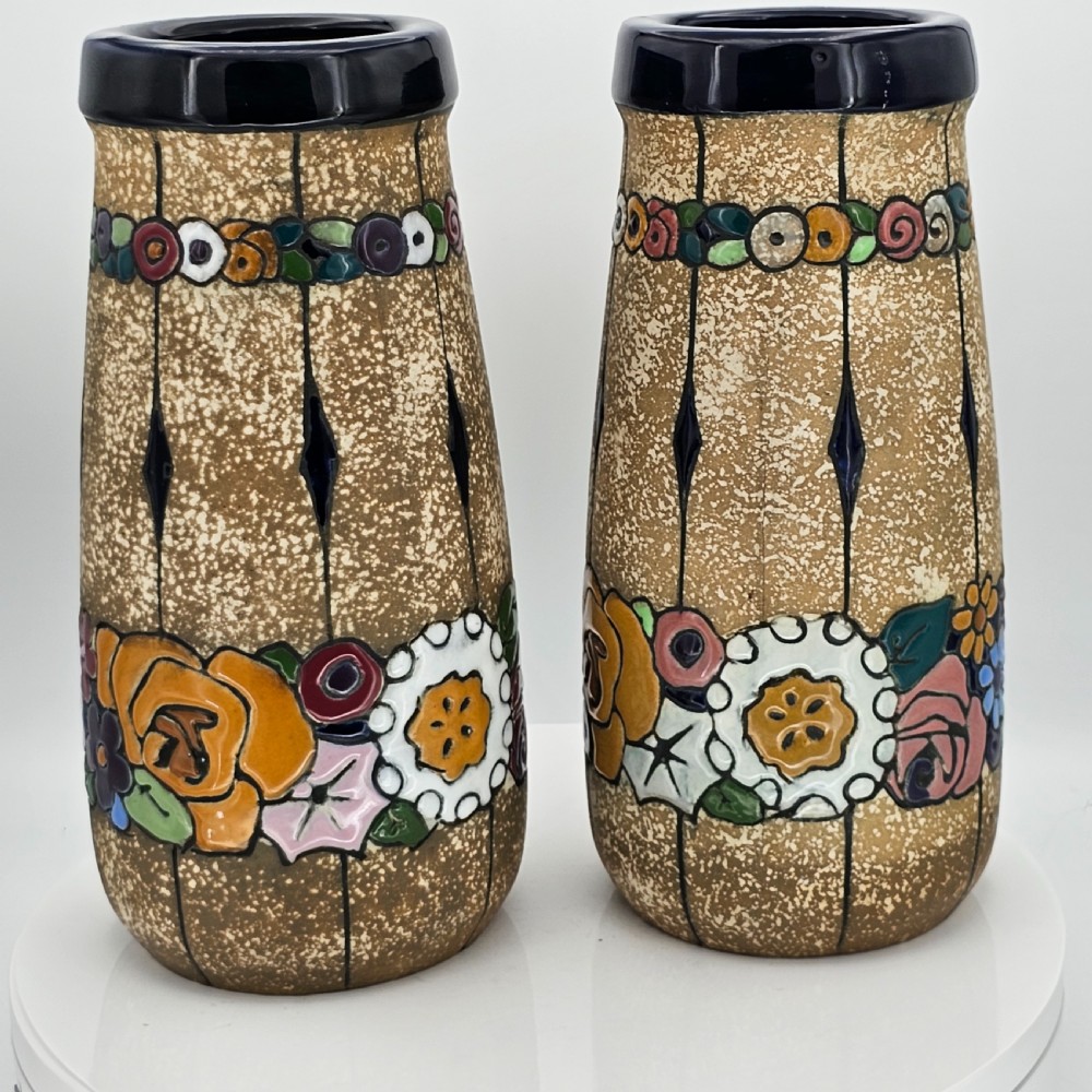 A pair of cylindrical Austrian ceramic vases featuring a textured beige ground, black rim, vertical cutouts, and colourful enamelled floral bands. View XX