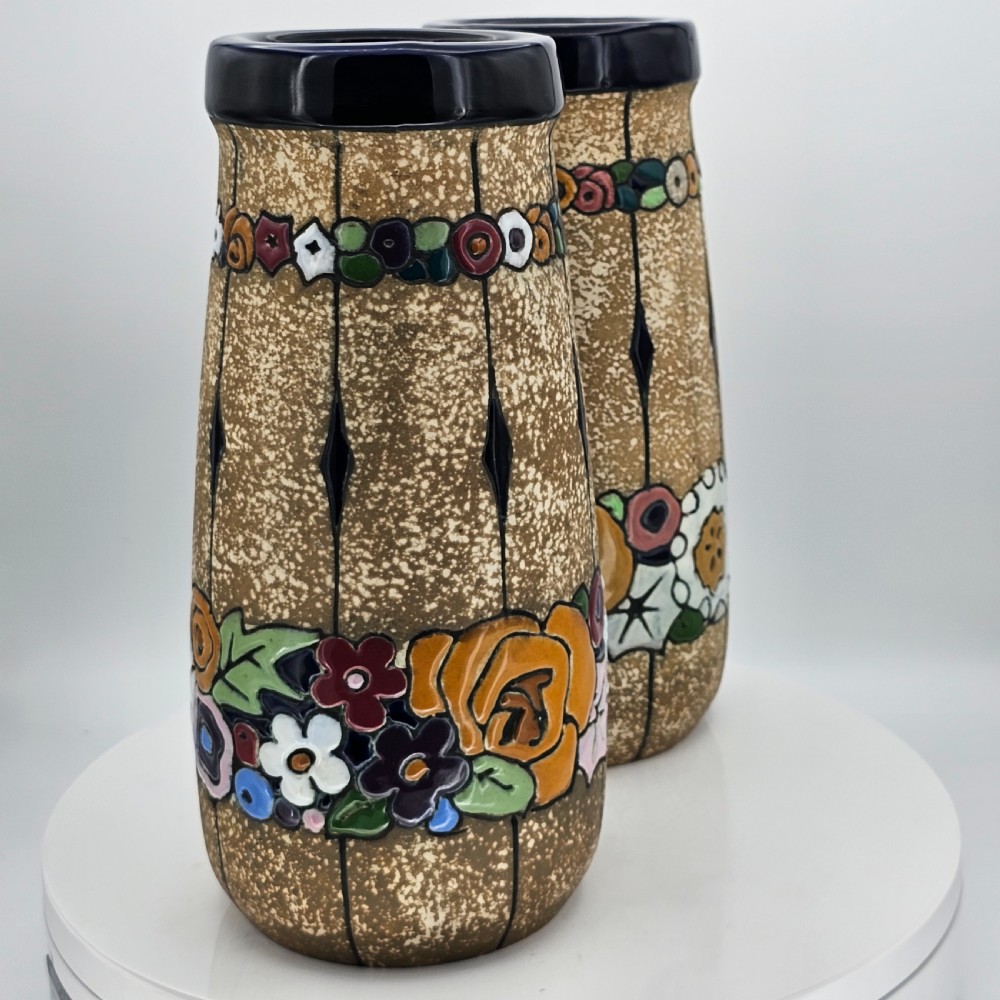 A pair of cylindrical Austrian ceramic vases featuring a textured beige ground, black rim, vertical cutouts, and colourful enamelled floral bands. View XXI