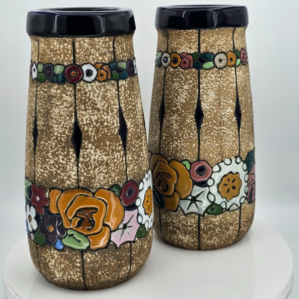 A pair of cylindrical Austrian ceramic vases featuring a textured beige ground, black rim, vertical cutouts, and colourful enamelled floral bands. View XXII