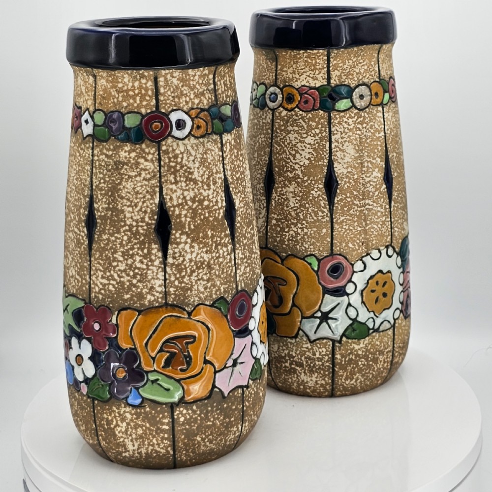 A pair of cylindrical Austrian ceramic vases featuring a textured beige ground, black rim, vertical cutouts, and colourful enamelled floral bands. View XXIII