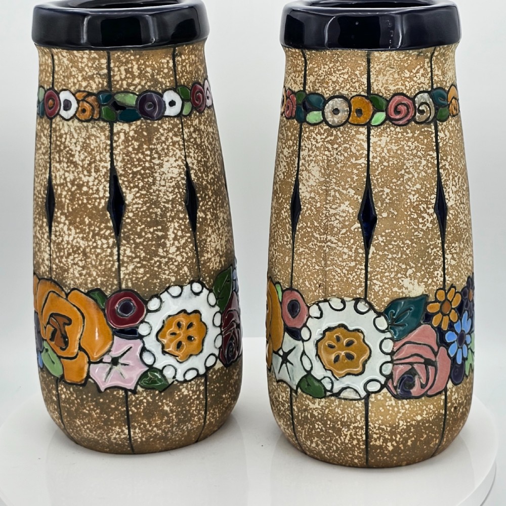 A pair of cylindrical Austrian ceramic vases featuring a textured beige ground, black rim, vertical cutouts, and colourful enamelled floral bands. View XXIV