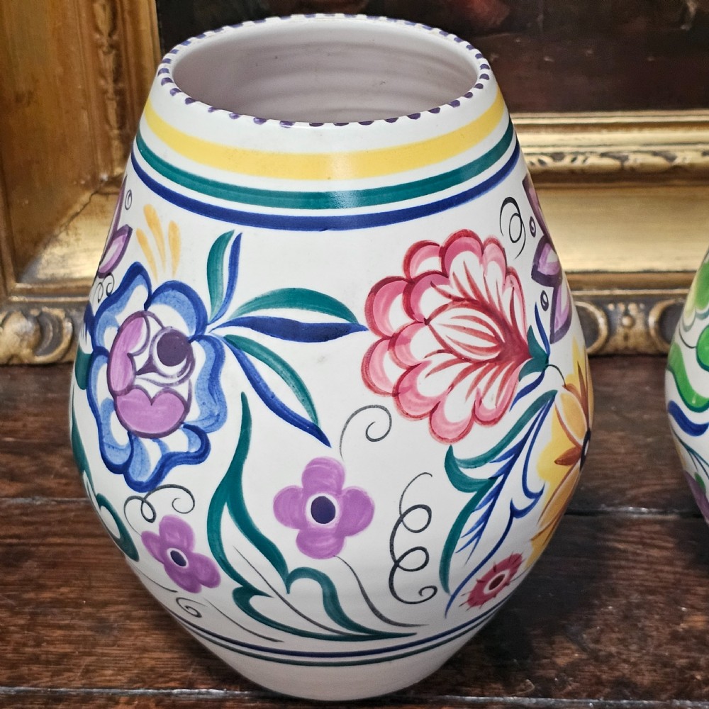 A pair of ovoid off-white ceramic vases decorated with hand-painted floral motifs in pink, purple, blue, green, and yellow. View V