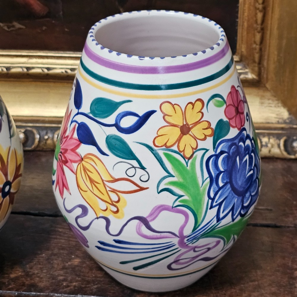 A pair of ovoid off-white ceramic vases decorated with hand-painted floral motifs in pink, purple, blue, green, and yellow. View VI
