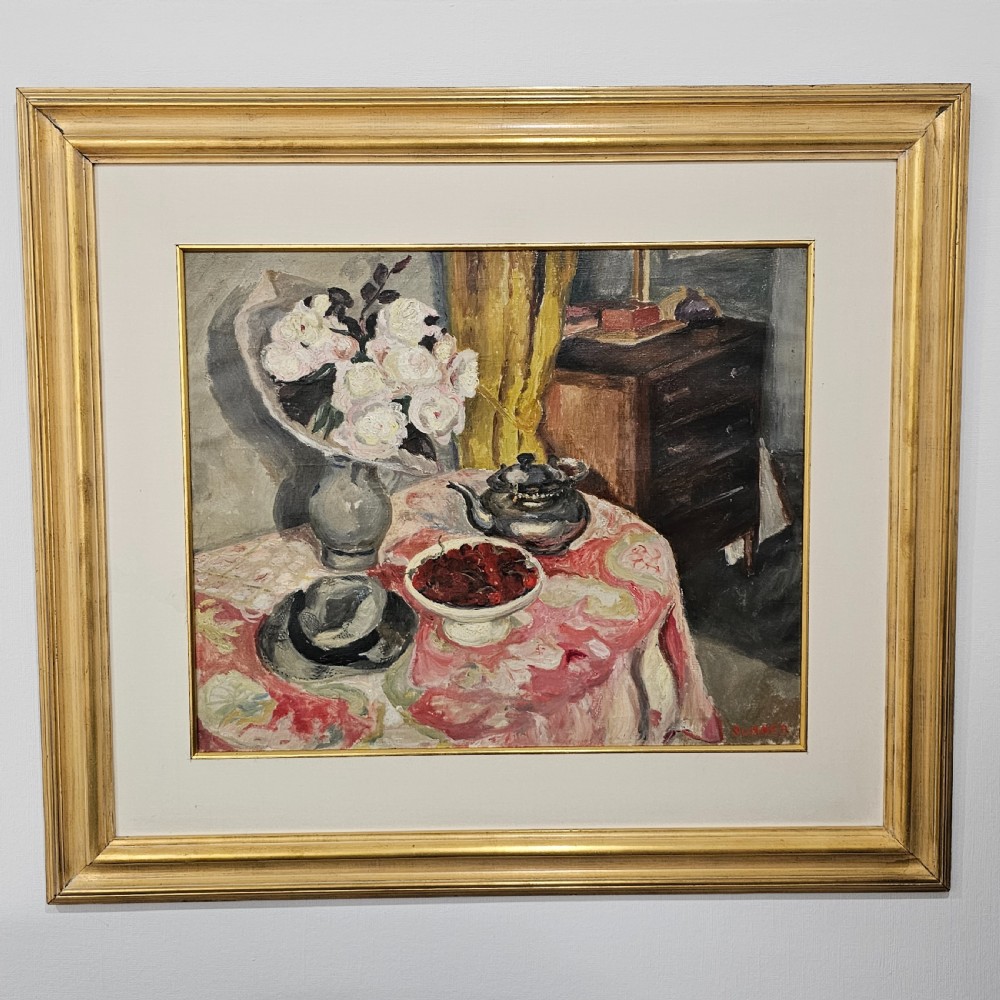A framed oil painting depicting a detailed still life scene with a vase of white flowers, a teapot, a bowl of cherries, and a hat on a pink patterned tablecloth.
