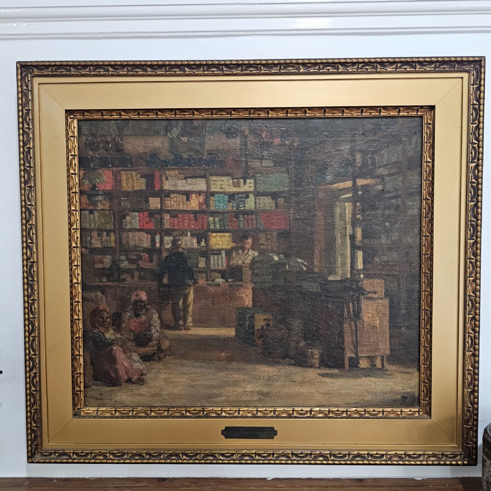 A framed oil painting depicting the interior of a village store in Namaqualand with seated figures and shelves of merchandise, set within a wide gold moulded frame. View II