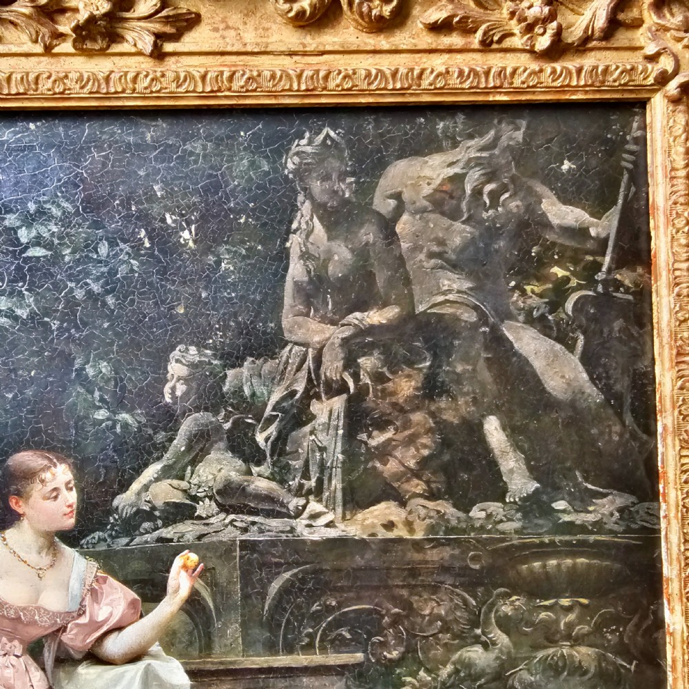 An 1880 framed oil painting depicting a woman in a pink dress beside a garden fountain with birds, presented in a heavily carved gilded frame. View VI