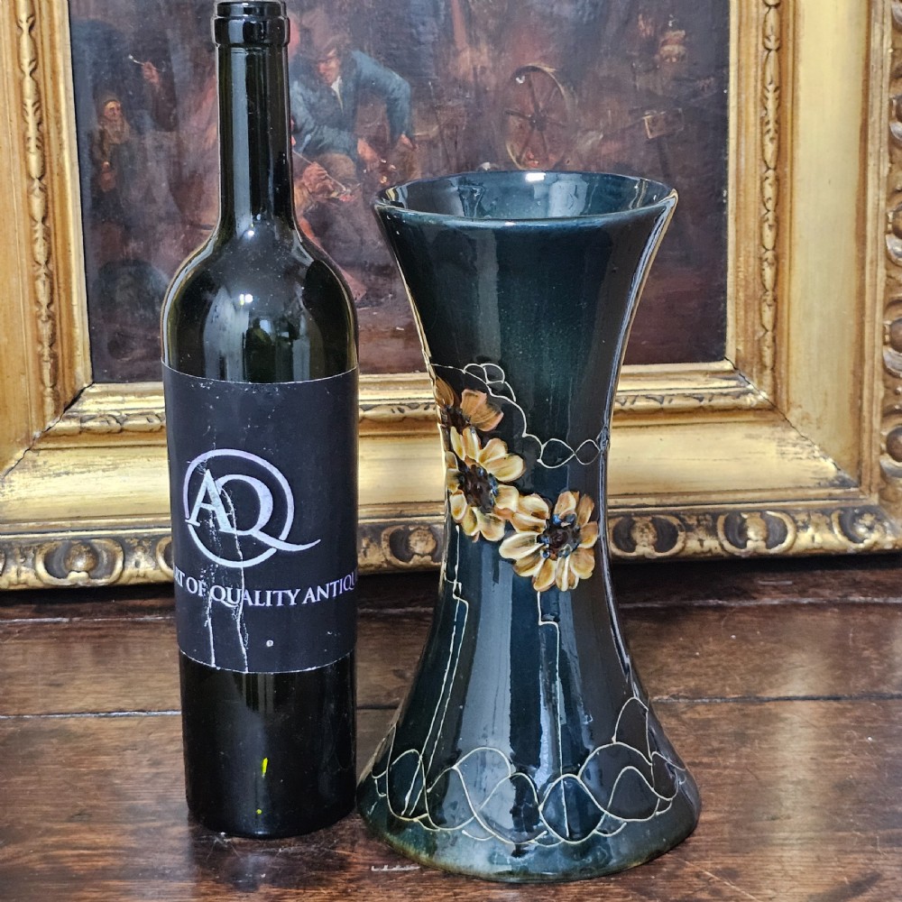 A dark green glazed earthenware vase with a flared top and base, featuring tube-lined ochre floral motifs and geometric line patterns. View XIII