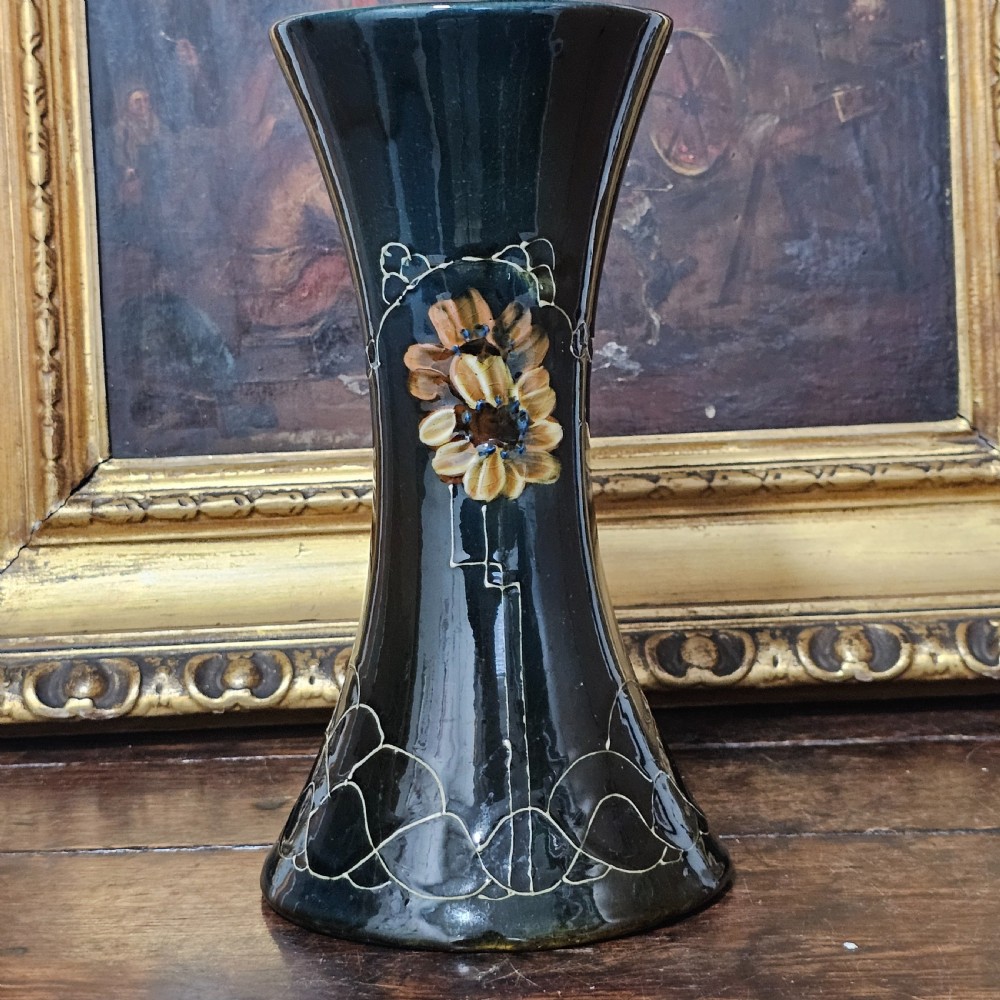 A dark green glazed earthenware vase with a flared top and base, featuring tube-lined ochre floral motifs and geometric line patterns. View VIII