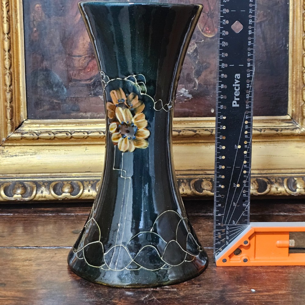 A dark green glazed earthenware vase with a flared top and base, featuring tube-lined ochre floral motifs and geometric line patterns. View XI