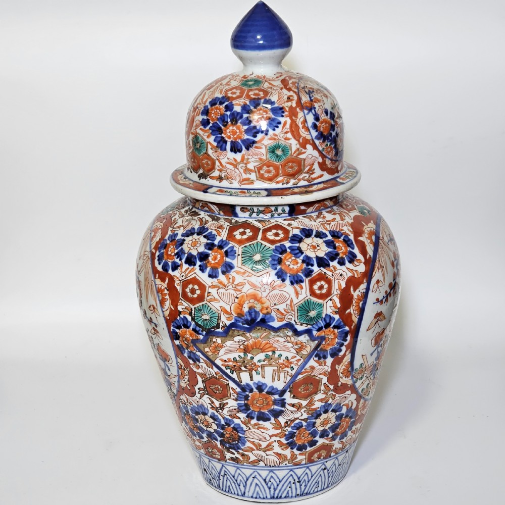 A 19th-century Japanese Imari porcelain ginger jar with a domed finial lid, decorated in hand-painted iron-red and cobalt blue floral cartouches. View II