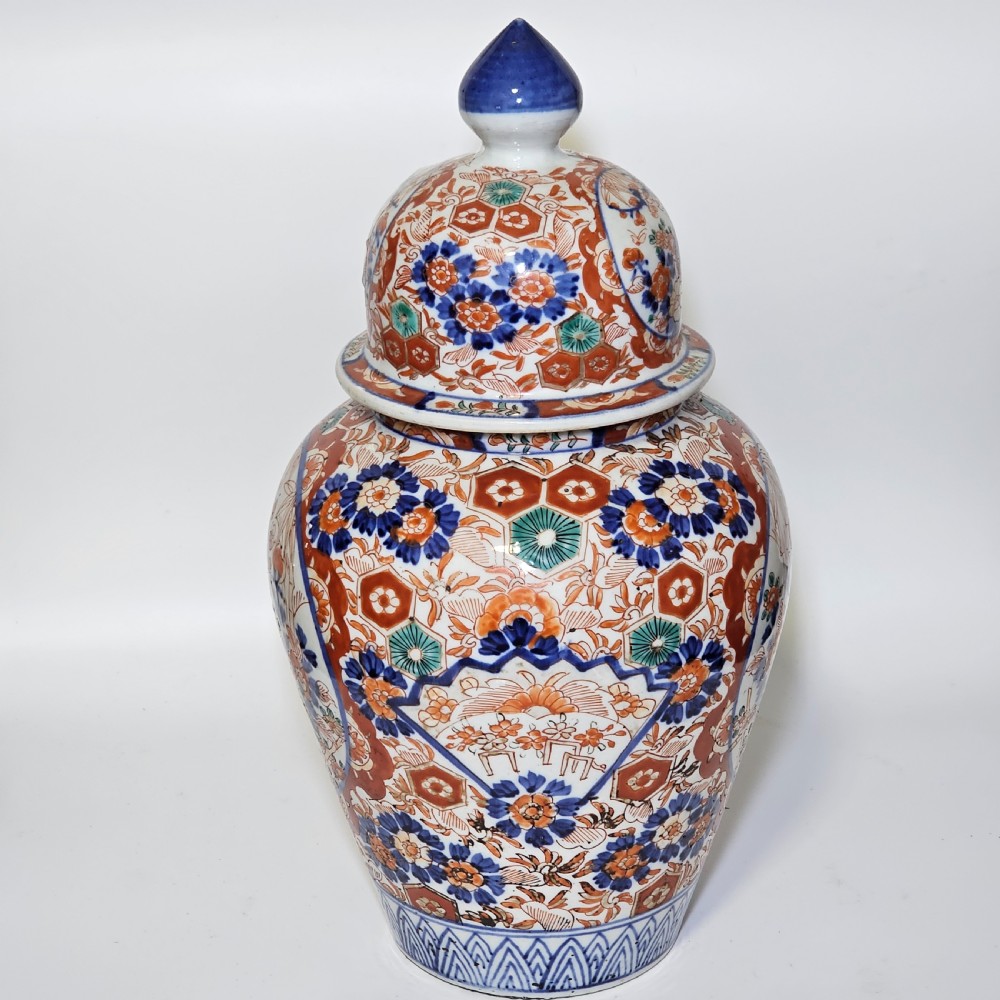 A 19th-century Japanese Imari porcelain ginger jar with a domed finial lid, decorated in hand-painted iron-red and cobalt blue floral cartouches. View V