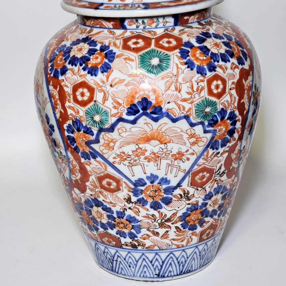 A 19th-century Japanese Imari porcelain ginger jar with a domed finial lid, decorated in hand-painted iron-red and cobalt blue floral cartouches. View VI