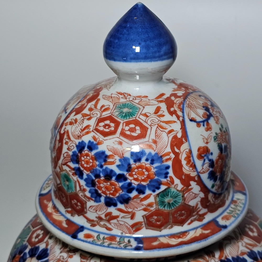 A 19th-century Japanese Imari porcelain ginger jar with a domed finial lid, decorated in hand-painted iron-red and cobalt blue floral cartouches. View IX