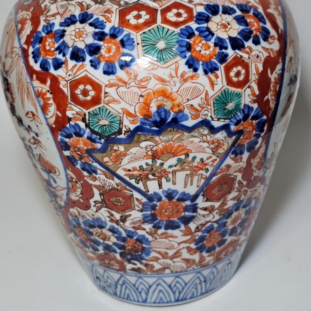 A 19th-century Japanese Imari porcelain ginger jar with a domed finial lid, decorated in hand-painted iron-red and cobalt blue floral cartouches. View X