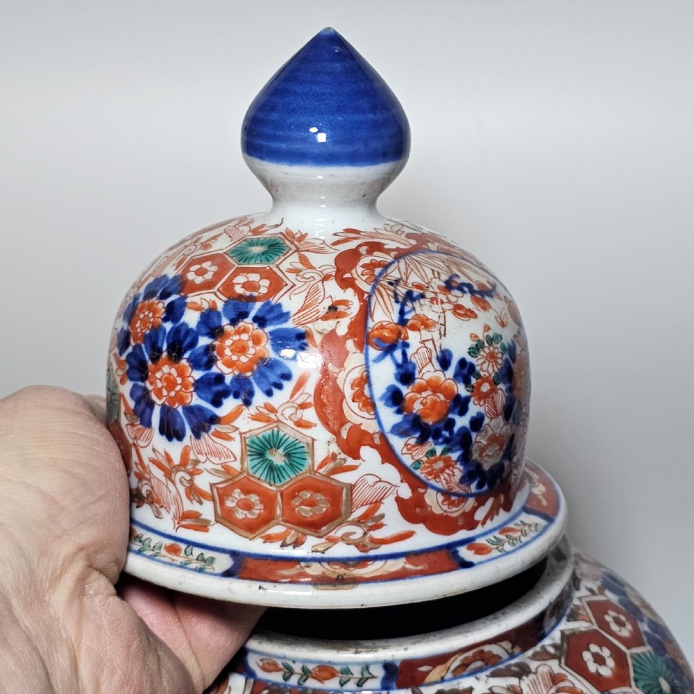 A 19th-century Japanese Imari porcelain ginger jar with a domed finial lid, decorated in hand-painted iron-red and cobalt blue floral cartouches. View XI
