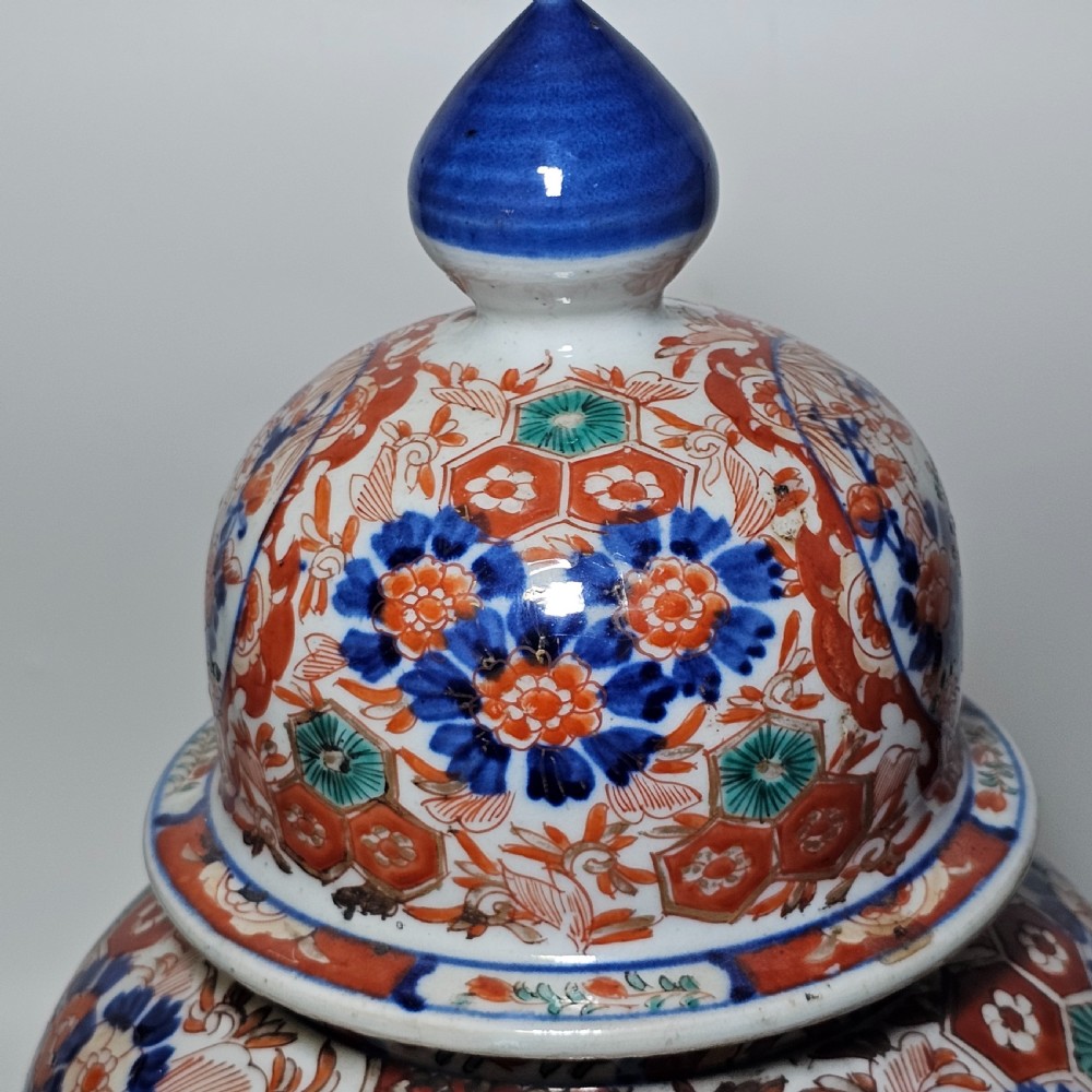 A 19th-century Japanese Imari porcelain ginger jar with a domed finial lid, decorated in hand-painted iron-red and cobalt blue floral cartouches. View XII