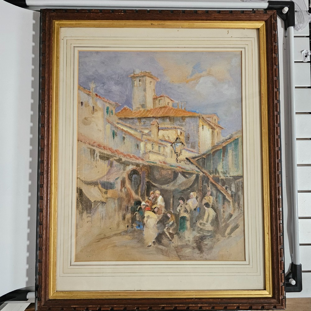 A framed Victorian watercolour painting depicting a European town market square with figures, architectural details, and a central tower in soft earth tones.