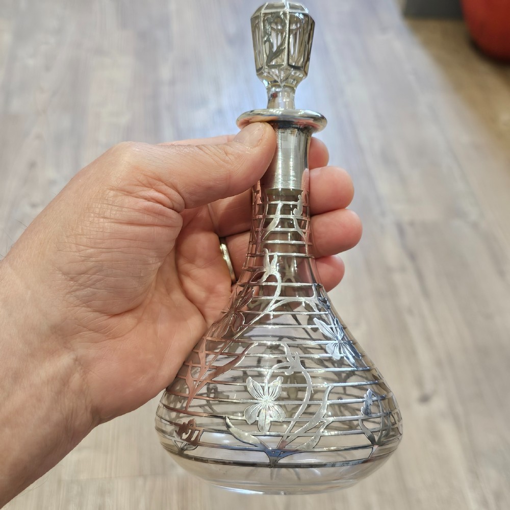 An early 20th-century glass decanter featuring an intricate sterling silver floral overlay and matching stopper. View II
