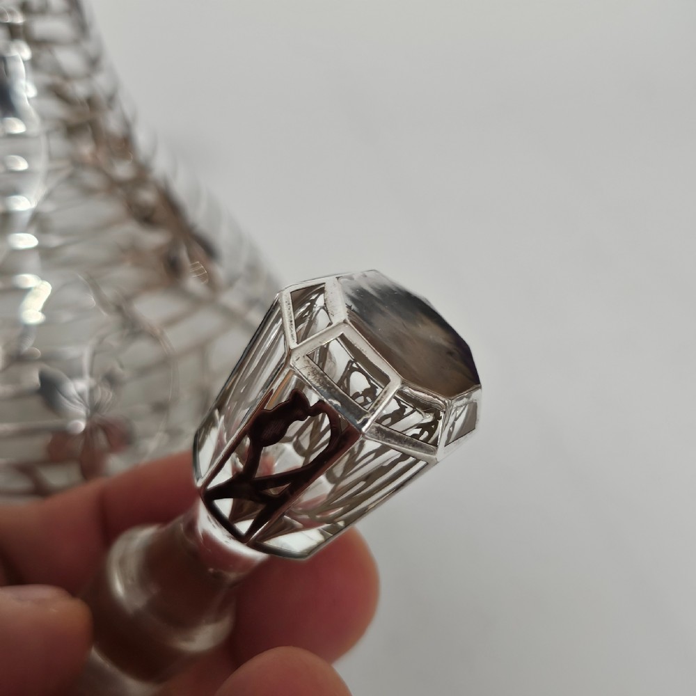 An early 20th-century glass decanter featuring an intricate sterling silver floral overlay and matching stopper. View VI