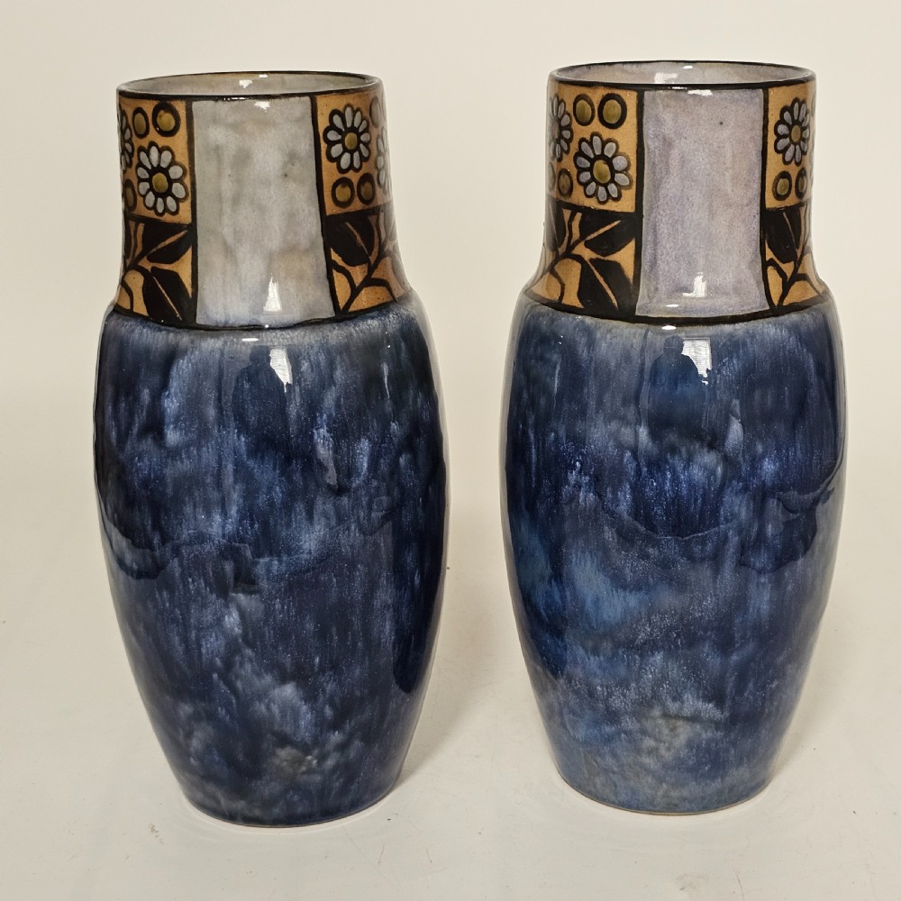 A pair of Royal Doulton stoneware vases featuring mottled blue glaze bodies and upper decorative bands with hand-painted floral motifs. View V