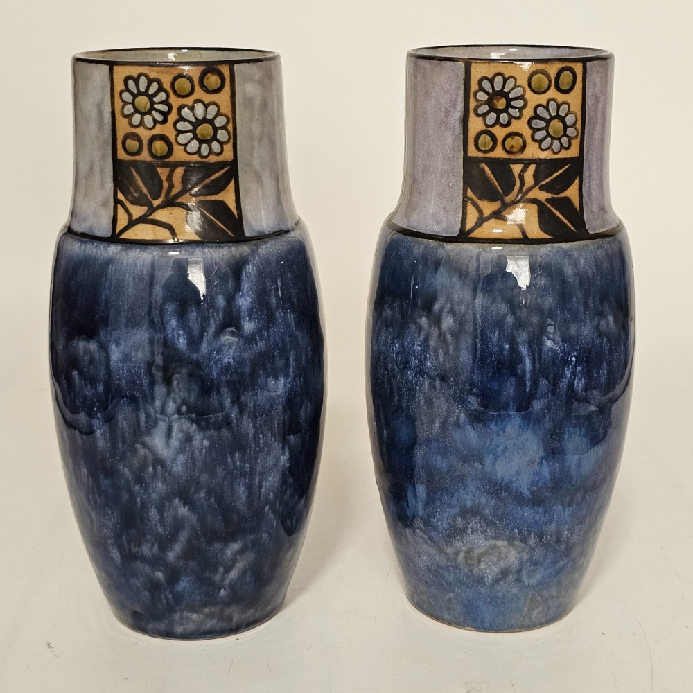 A pair of Royal Doulton stoneware vases featuring mottled blue glaze bodies and upper decorative bands with hand-painted floral motifs. View VI
