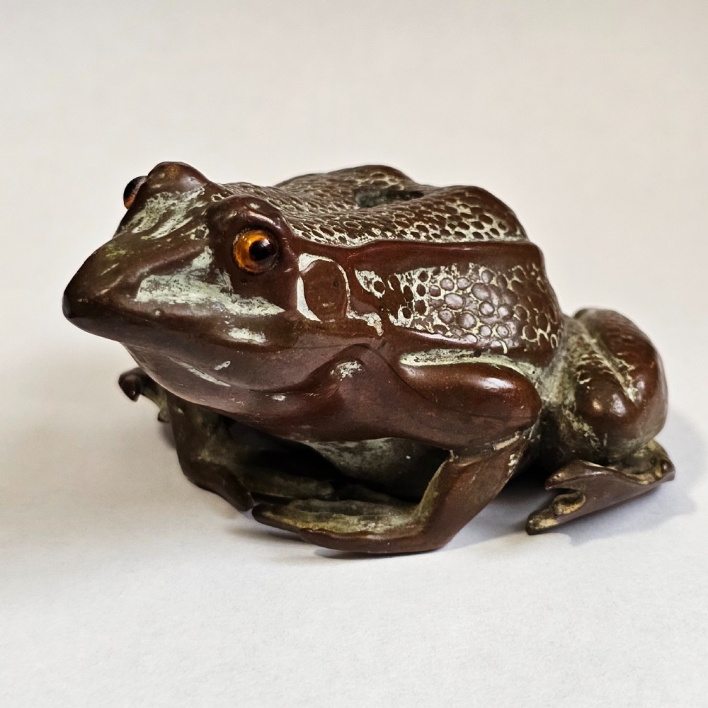 An antique cast bronze frog pen holder featuring textured skin details and inset glass eyes. View IV