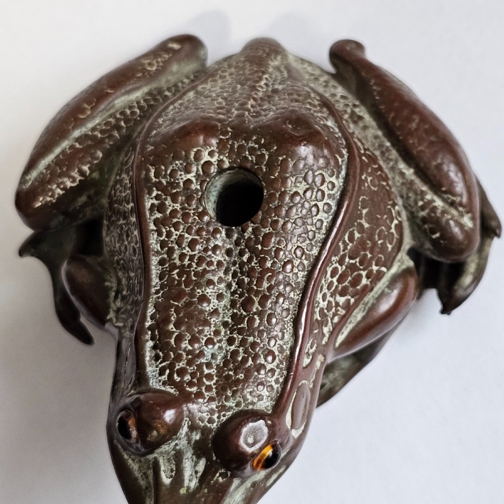 An antique cast bronze frog pen holder featuring textured skin details and inset glass eyes. View V