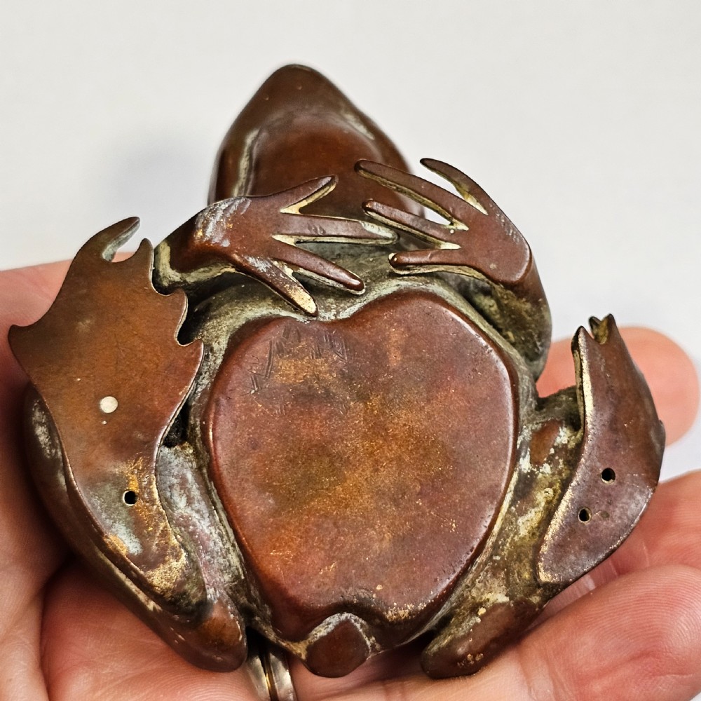 An antique cast bronze frog pen holder featuring textured skin details and inset glass eyes. View IX