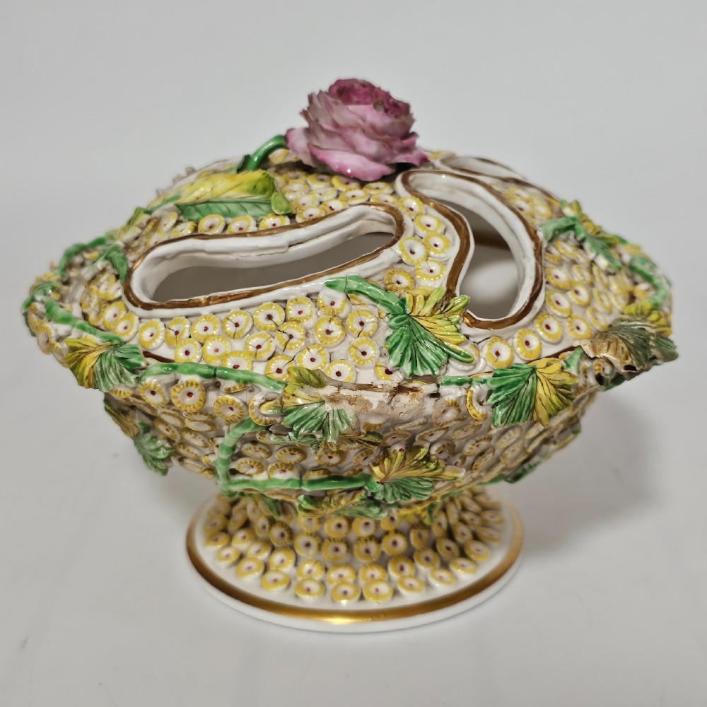 An antique circa 1830 Spode porcelain potpourri bowl with a pierced lid, featuring dense encrusted yellow and green flowers and a central pink rose finial.