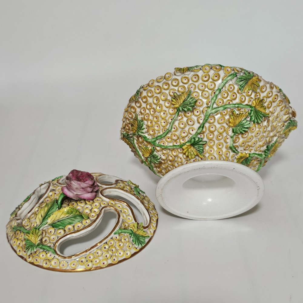 An antique circa 1830 Spode porcelain potpourri bowl with a pierced lid, featuring dense encrusted yellow and green flowers and a central pink rose finial. View VI
