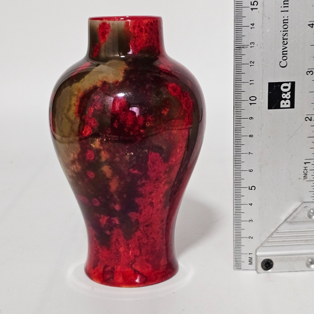 A glossy ceramic vase featuring a mottled flambe glaze transitioning from deep crimson red to dark tones at the neck. View III