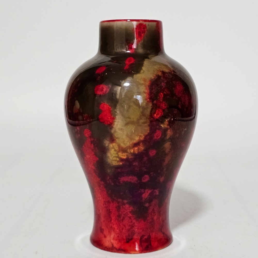 A glossy ceramic vase featuring a mottled flambe glaze transitioning from deep crimson red to dark tones at the neck. View IV
