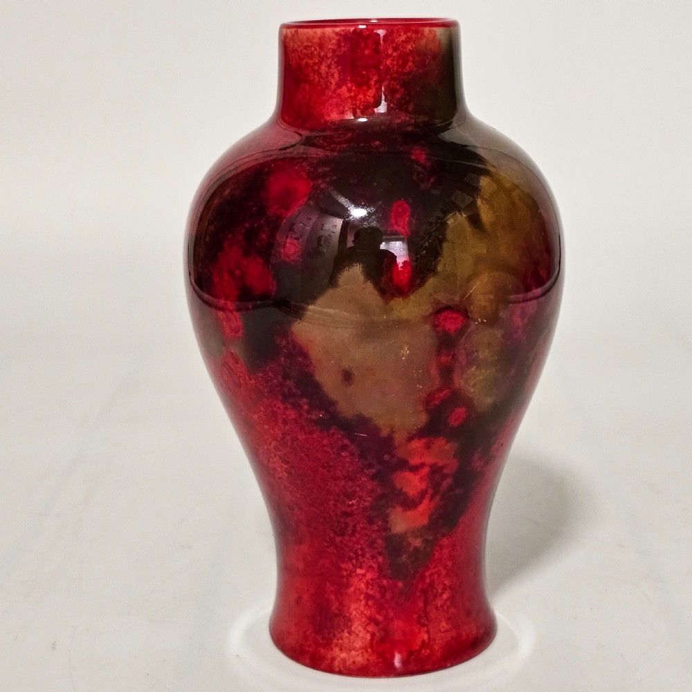 A glossy ceramic vase featuring a mottled flambe glaze transitioning from deep crimson red to dark tones at the neck. View V