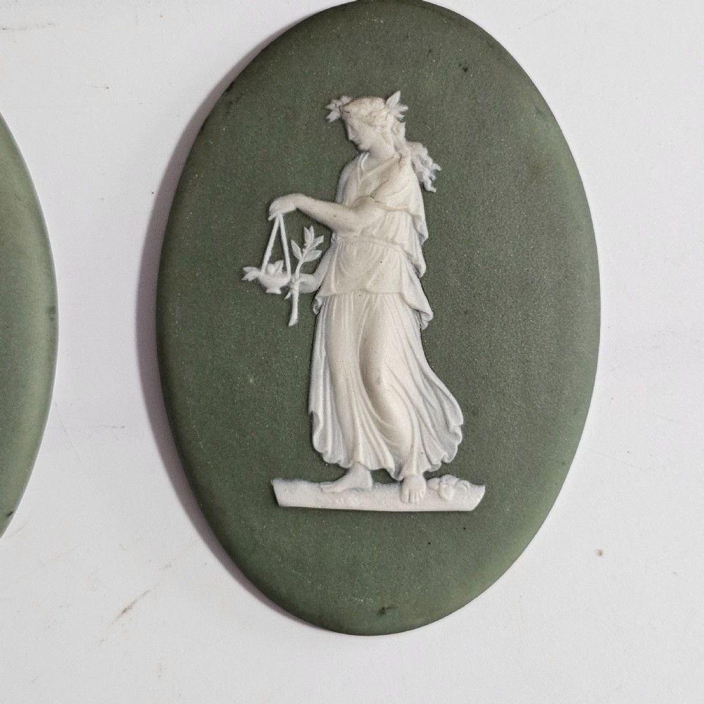A pair of oval sage green stoneware plaques decorated with raised white relief figures in classical drapery. View II