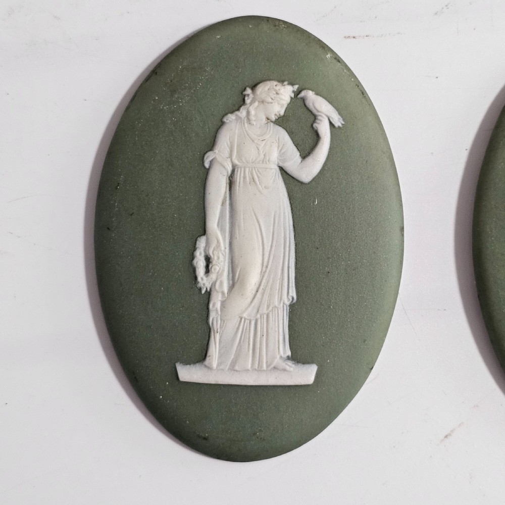 A pair of oval sage green stoneware plaques decorated with raised white relief figures in classical drapery. View III