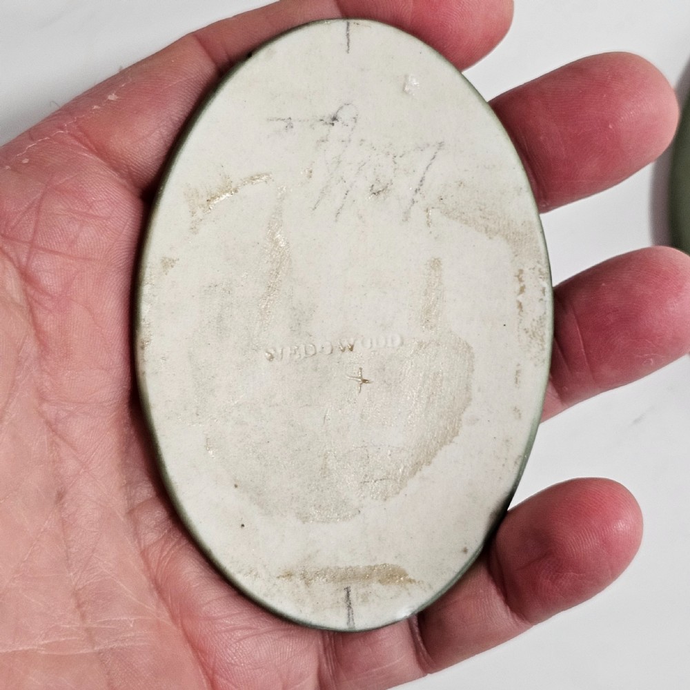 A pair of oval sage green stoneware plaques decorated with raised white relief figures in classical drapery. View V