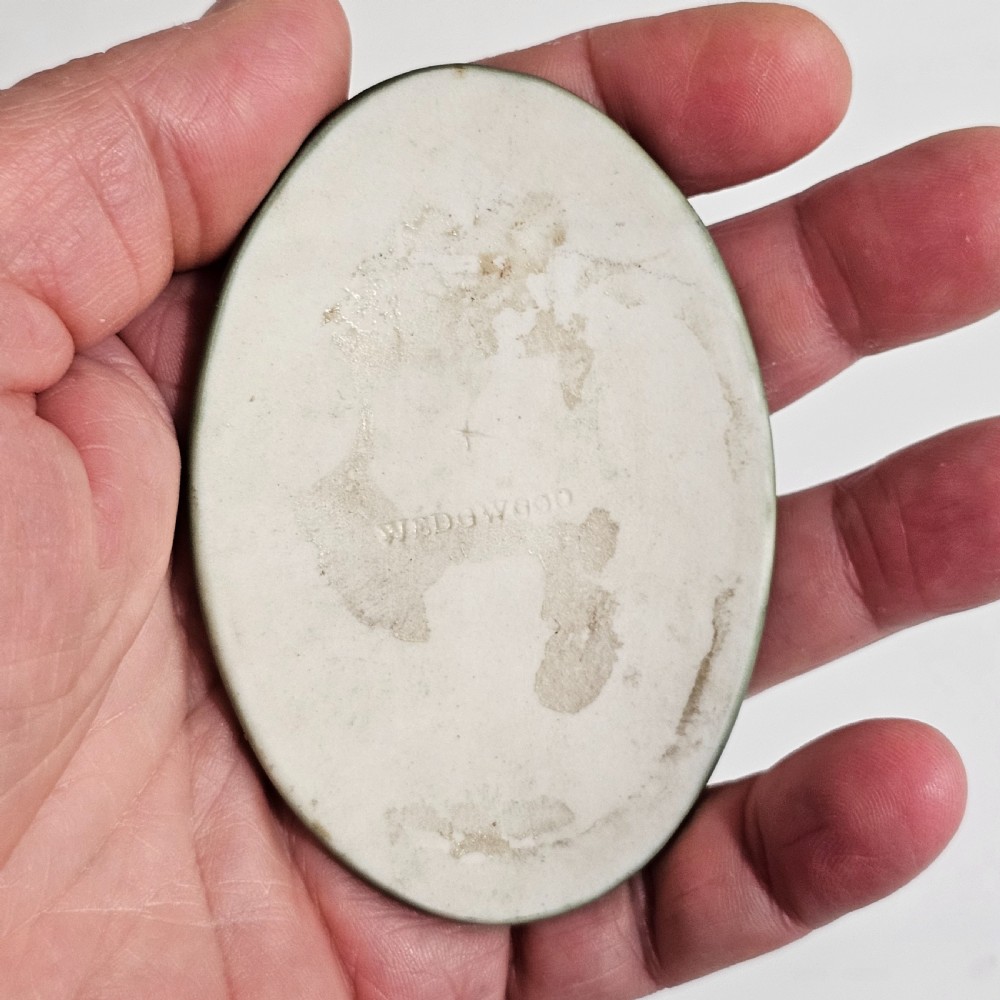 A pair of oval sage green stoneware plaques decorated with raised white relief figures in classical drapery. View VII