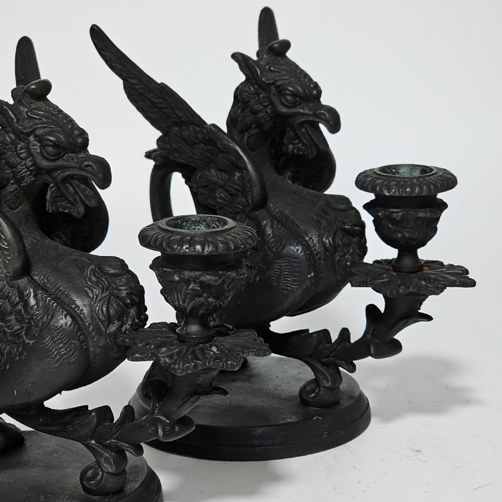 A pair of heavy dark bronze chambersticks featuring mythical griffin figures holding candle nozzles. View III