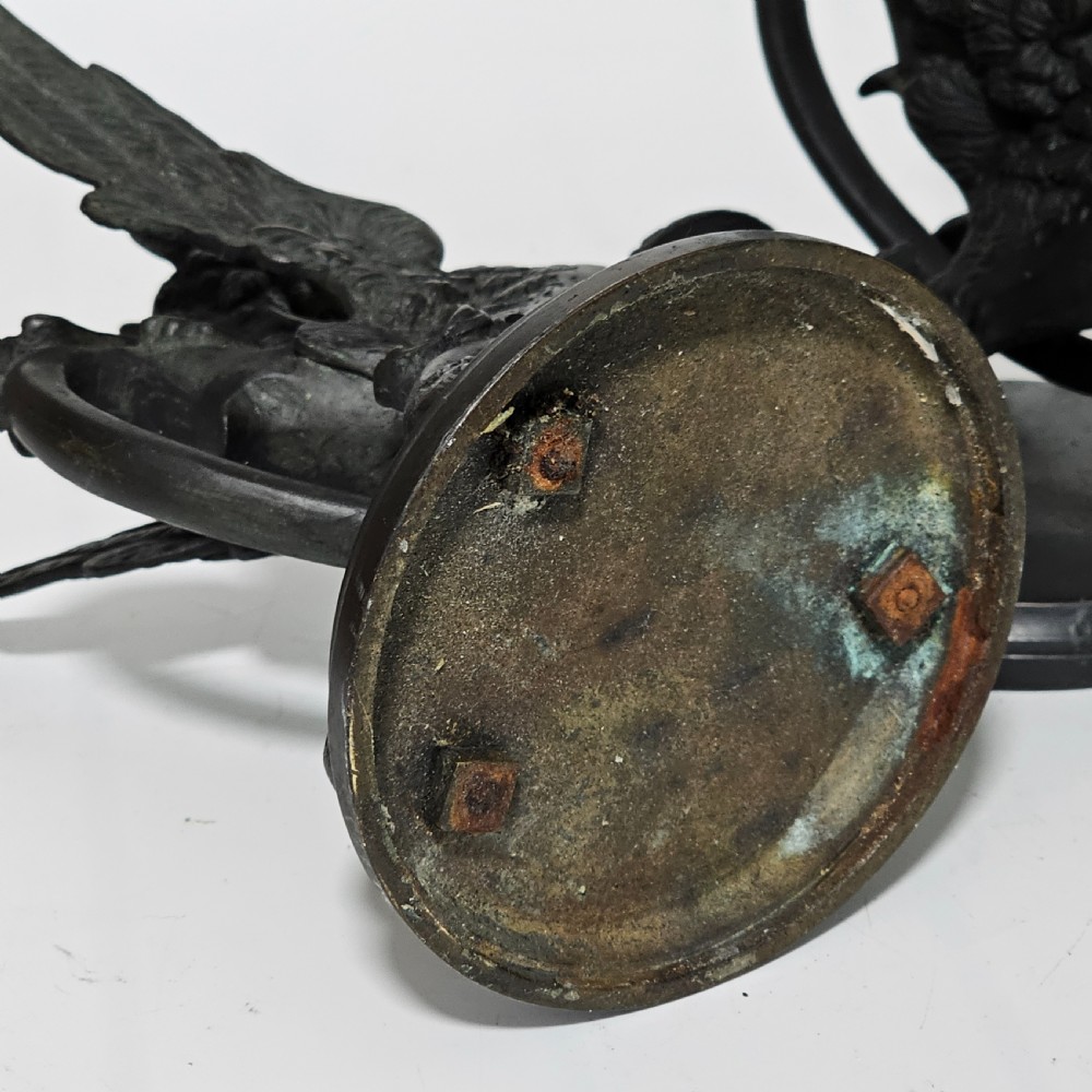A pair of heavy dark bronze chambersticks featuring mythical griffin figures holding candle nozzles. View IV